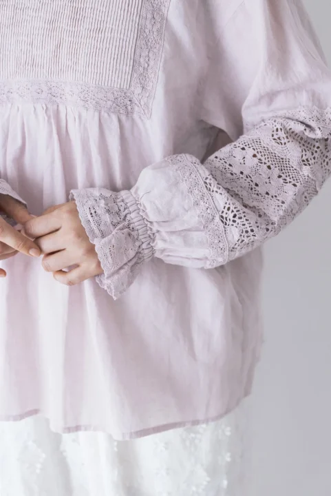 淡いパープル色のブラウスに施された繊細なレースとピンタックのディテール