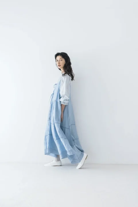 水色のロングワンピースと白いブラウスを着用した女性