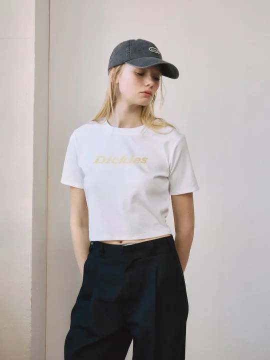 白いクロップTシャツと黒いパンツ、キャップを着用した女性