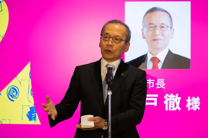 スーツ姿の男性がマイクを前にスピーチを行っている