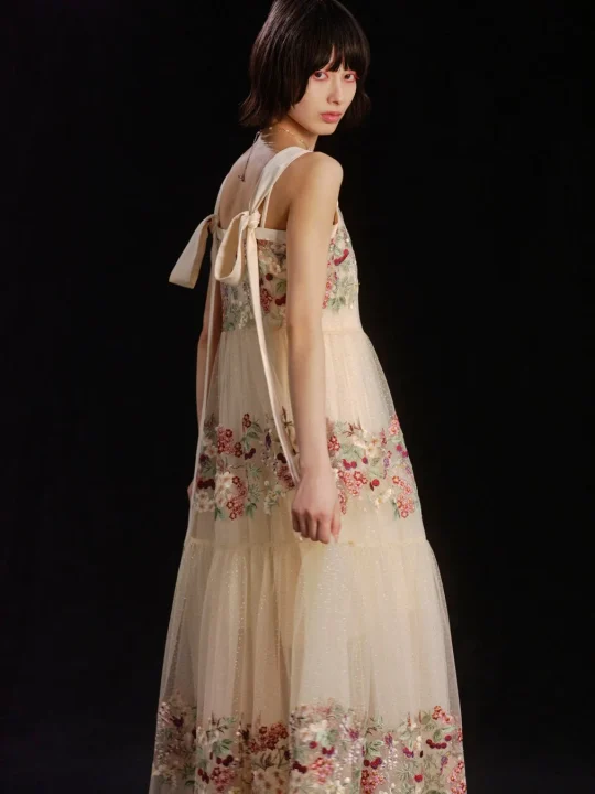 花柄の刺繍が施されたクリーム色のロングドレスを着用したモデル