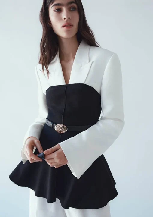 白と黒のバイカラーのトップスに、ゴールドのバックルが付いたベルトを着用した女性のファッションポートレート