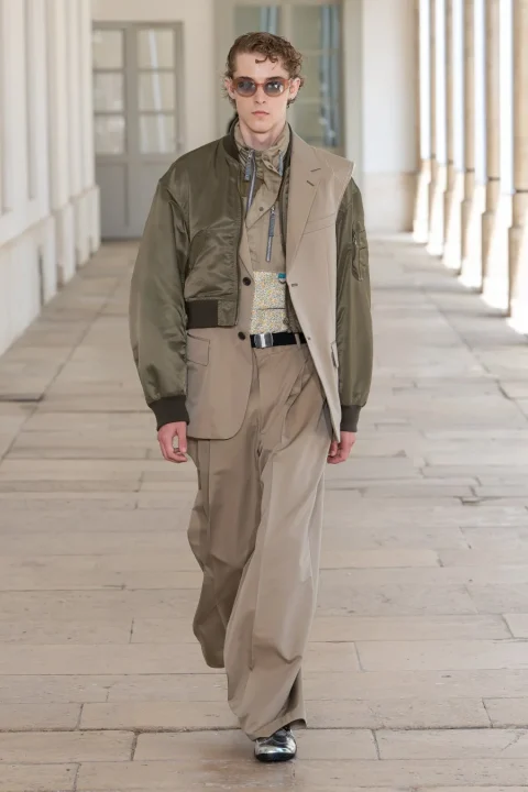 カーキのボンバージャケットとベージュのブレザーを重ね着した男性モデル