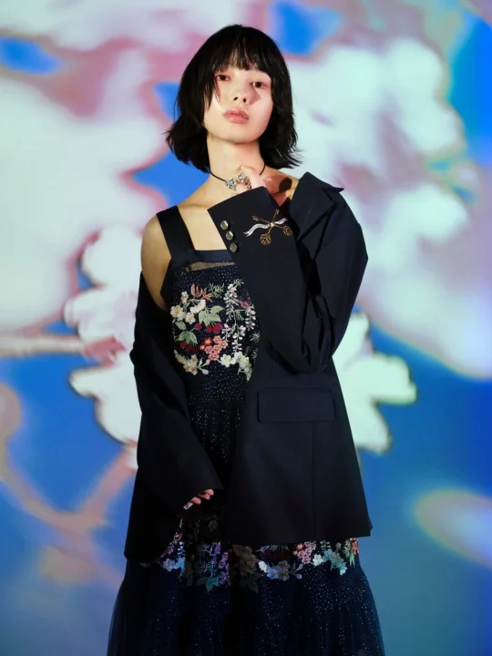花柄の刺繍が施されたドレスとジャケットを着用したモデル