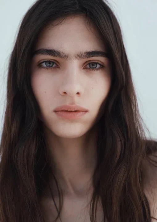 暗いウェーブヘアと印象的な青みがかった瞳を持つ若い女性のクローズアップポートレート