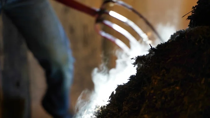 ピッチフォークで堆肥をかき混ぜる人物