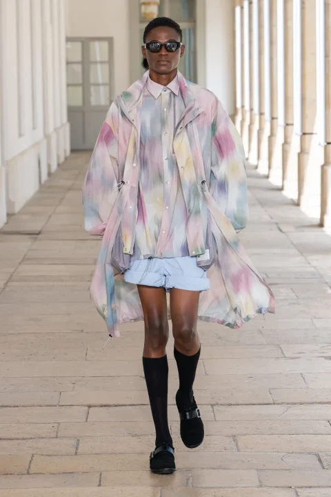 カラフルなタイダイ柄のロングジャケットとシャツを着用したモデル