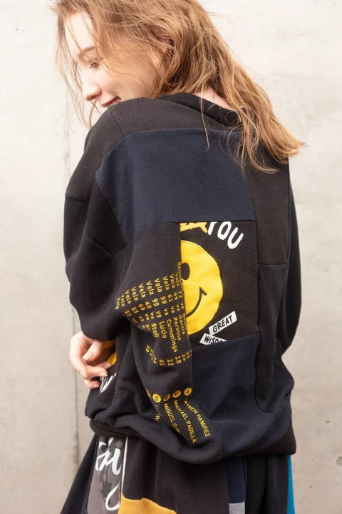 スマイリーフェイスのパッチワークスウェットを着用した女性モデル