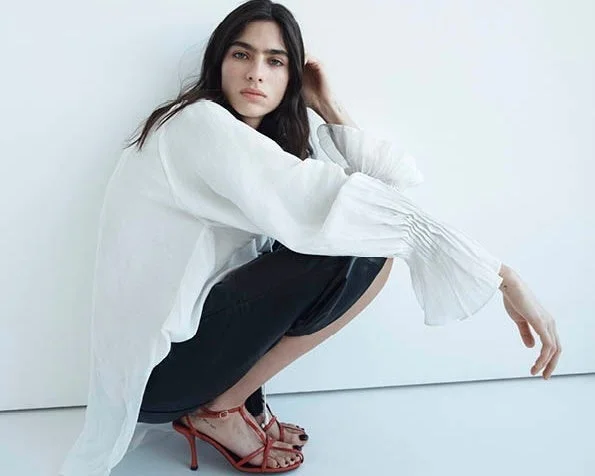 白シャツと黒ショートパンツ、赤サンダルを着用した女性のファッションポートレート