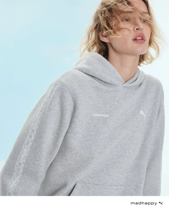 グレーのmadhappyとPumaのロゴ入りパーカーを着た金髪のモデル