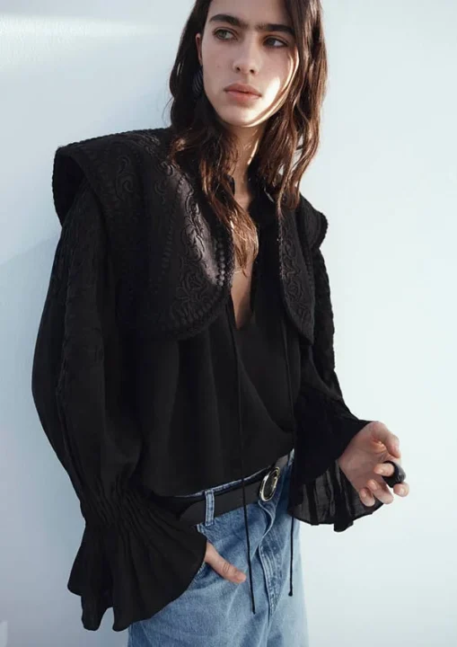 黒い刺繍入りのブラウスとデニムを着用した女性のポートレート