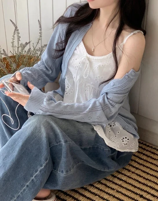 水色のニットカーディガンと白いレースキャミソール、ワイドデニムを着用した人物