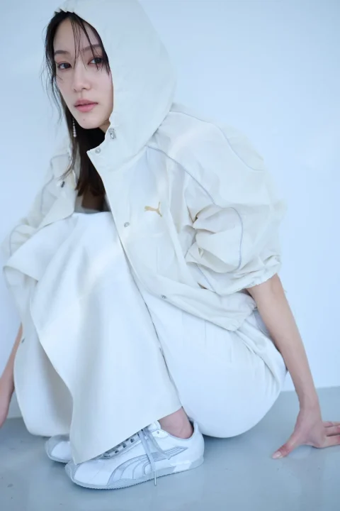 白いフーディジャケットとパンツ、PUMAのスニーカーを着用した女性