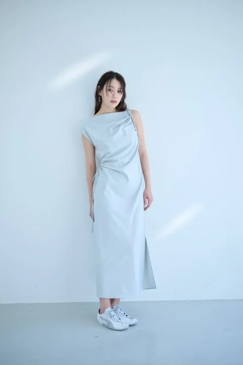 ライトブルーのドローストリングデザインのロングワンピースを着用した女性