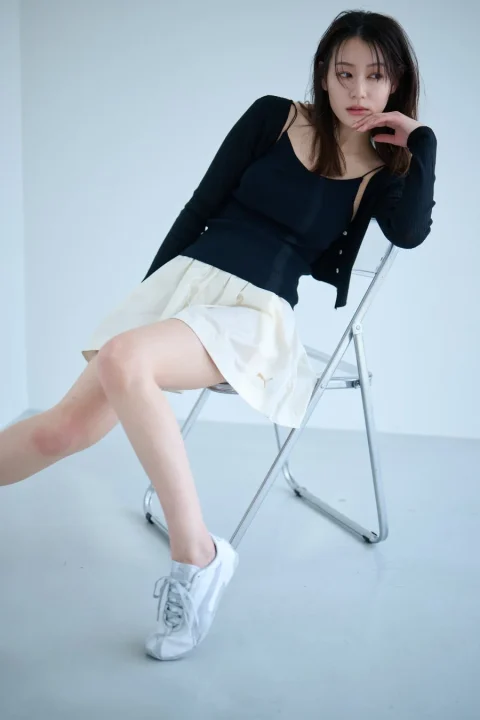 白いスタジオで椅子に座る若い女性