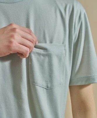 水色のTシャツの胸ポケットに手が入れられているクローズアップ画像