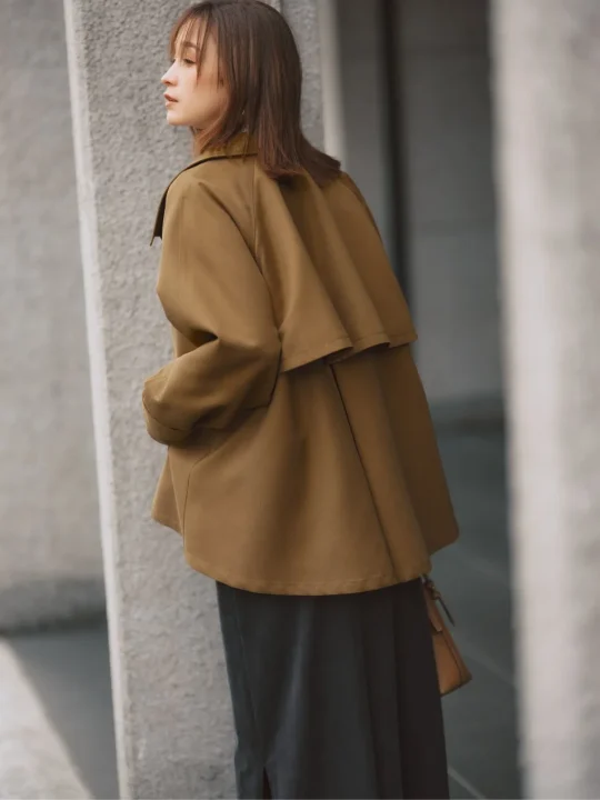 茶色のアウターと黒いスカートを着用した藤井サチさんの横顔