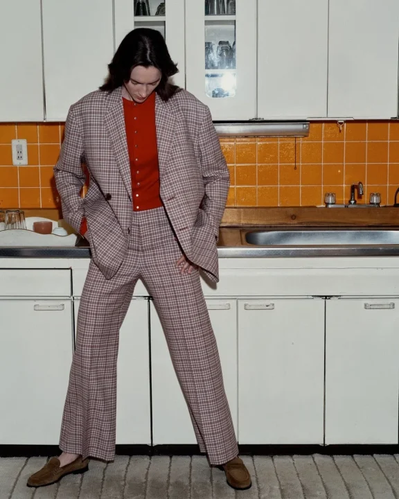 チェック柄のスーツと赤いカーディガンを着用した人物