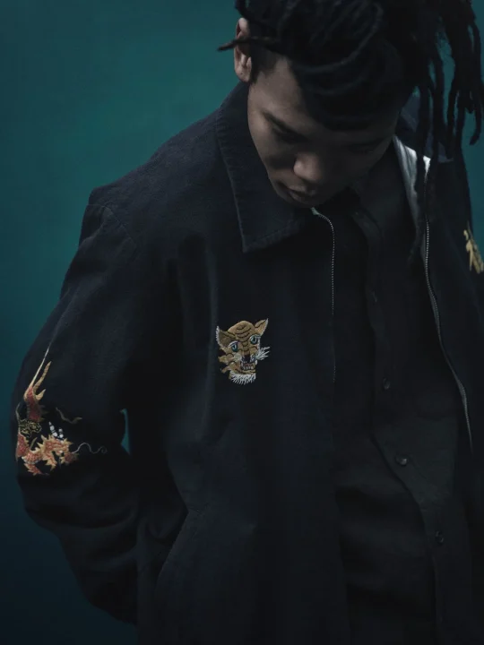 虎と龍の刺繍が施されたジャケットを着用した男性