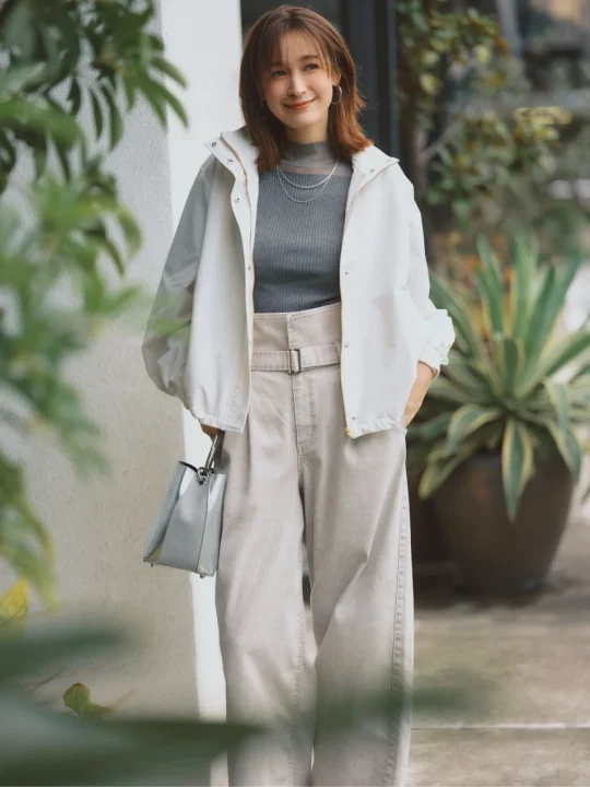 白いアウターとグレーのトップス、ベージュのワイドパンツを着用した藤井サチさんの大人カジュアルなコーディネート