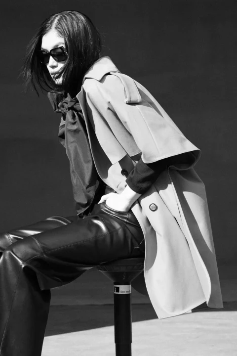 トレンチコートとレザーパンツを着用した女性のモノクロポートレート