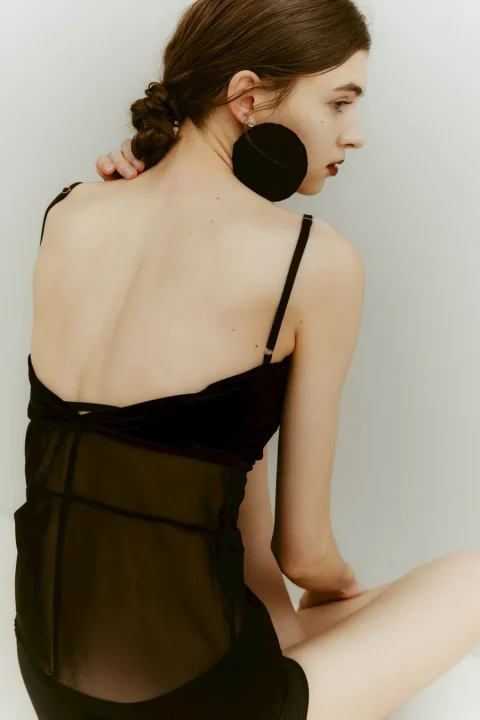 黒いシアー素材のキャミソールと大きな円形イヤリングをつけた女性