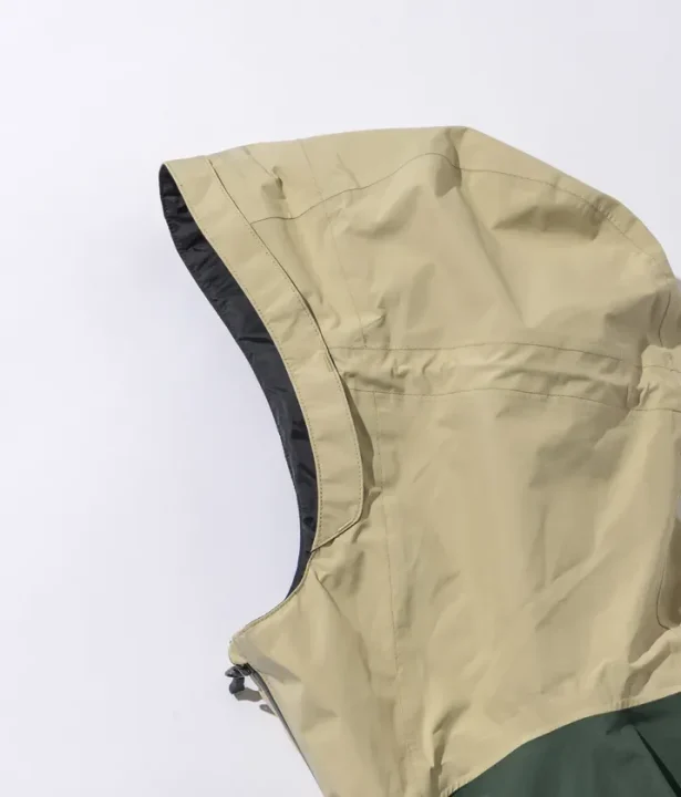 ベージュとダークグリーンのツートーンカラーのフード付きジャケットの一部