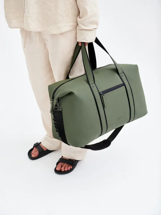 カーキ色のダッフルバッグを持つ人物