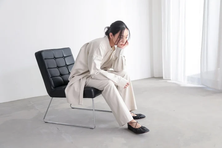 ベージュのセットアップを着た女性が椅子に座っている