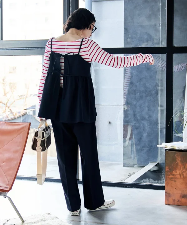 ストライプのトップスに黒のキャミソールとワイドパンツを重ね着した女性