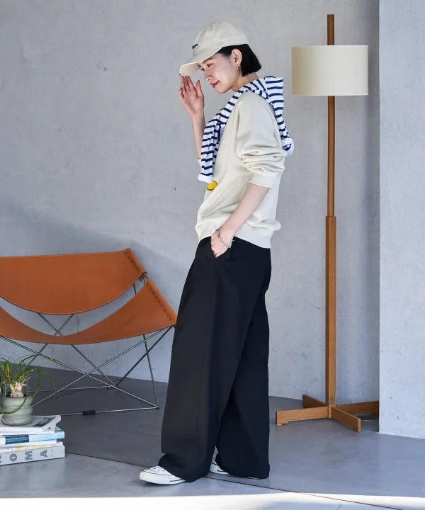 ベージュのスウェットに黒のワイドパンツ、キャップを合わせた女性