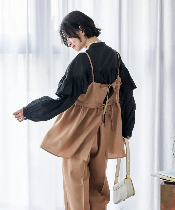 黒のフリルブラウスとブラウンのキャミソール、ワイドパンツを合わせた女性の全身コーディネート