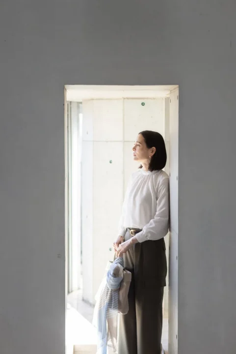 白いブラウスとダークカラーのパンツを着用した女性