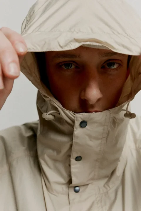ベージュのフード付きジャケットを着用した男性モデルのクローズアップ