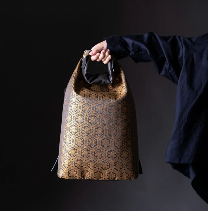 日本の伝統的な亀甲花菱のような幾何学模様が施された金色と紺色のバッグ