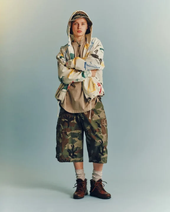 柄物のフーディーと迷彩柄ショートパンツを着用した人物