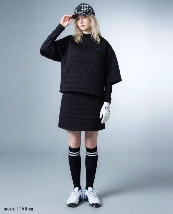 黒いキルティング素材のゴルフウェア（トップスとスカート）を着用した女性モデルの全身画像