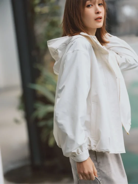 白いフード付きジャケットを着用した藤井サチさんのポートレート