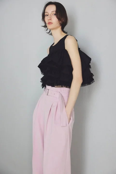 黒いフリルのノースリーブトップスとピンクのワイドパンツ