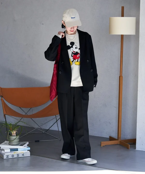 ミッキーマウスのスウェットに黒のブレザーとワイドパンツを合わせた女性