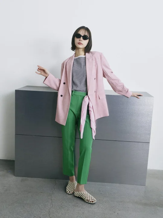 ピンクのダブルジャケットと鮮やかなグリーンのパンツ