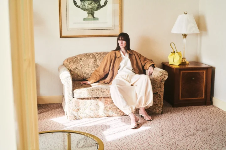 茶色のジャケットと淡いパンツの女性