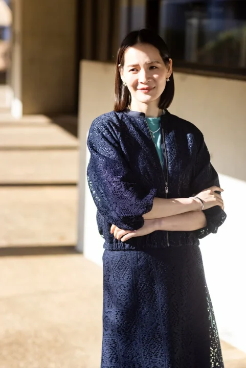 ネイビーのレース素材のジャケットとスカートを着用した女性