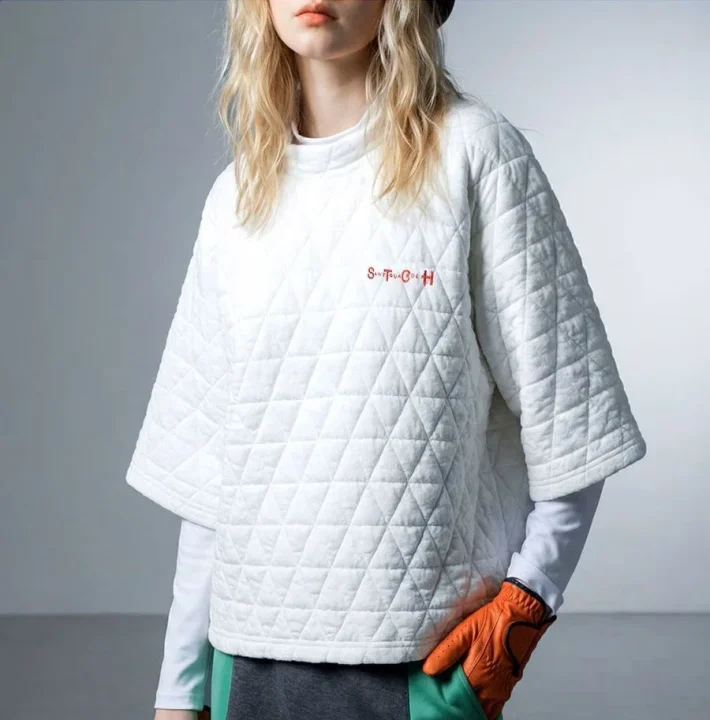 白いキルティングのモックネックトップスを着用した女性の画像