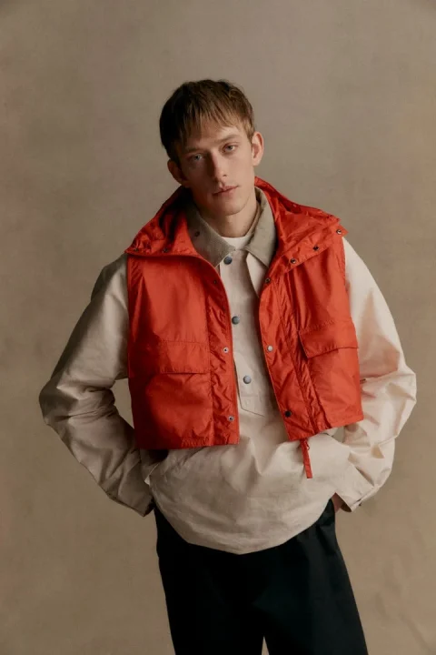 オレンジ色のベストとベージュのシャツを着用した男性モデル