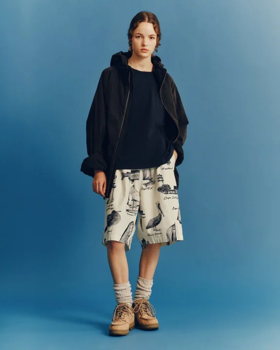 船や鳥、灯台などのイラストが描かれたショートパンツを着用した人物