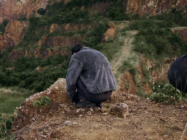 フリースジャケットを着てしゃがむ人物の後ろ姿