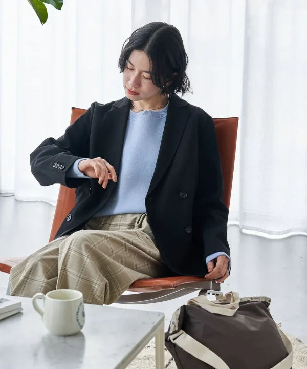 黒いジャケットと水色のセーター、チェック柄のスカートを着用した女性