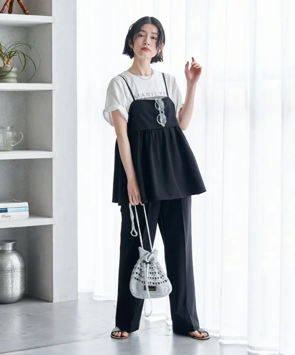 白いTシャツに黒いキャミワンピースとワイドパンツを合わせたモノトーンコーデの女性