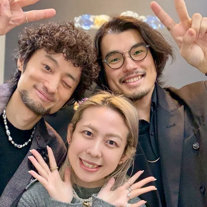 笑顔でポーズをとる3人の男女の集合写真です。